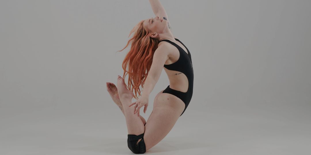 pole dancer wearing pole wear body suit and kneepads in black
